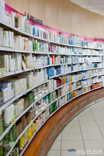 Dans une pharmacie, une photo mettant en valeur les rayonnages de médicaments et autres produits de soins et d'hygiène.