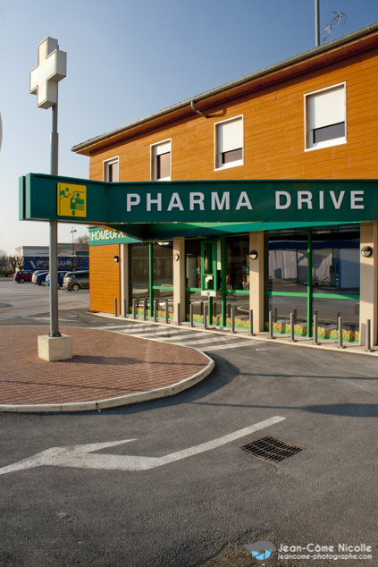 Vue extérieure d'ensemble d'un guichet de pharma drive dans une pharmacie pour la délivrance de médicaments ou de produits de soins et d'hygiène sans descendre de la voiture.
